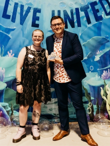 two people smiling while one holds award