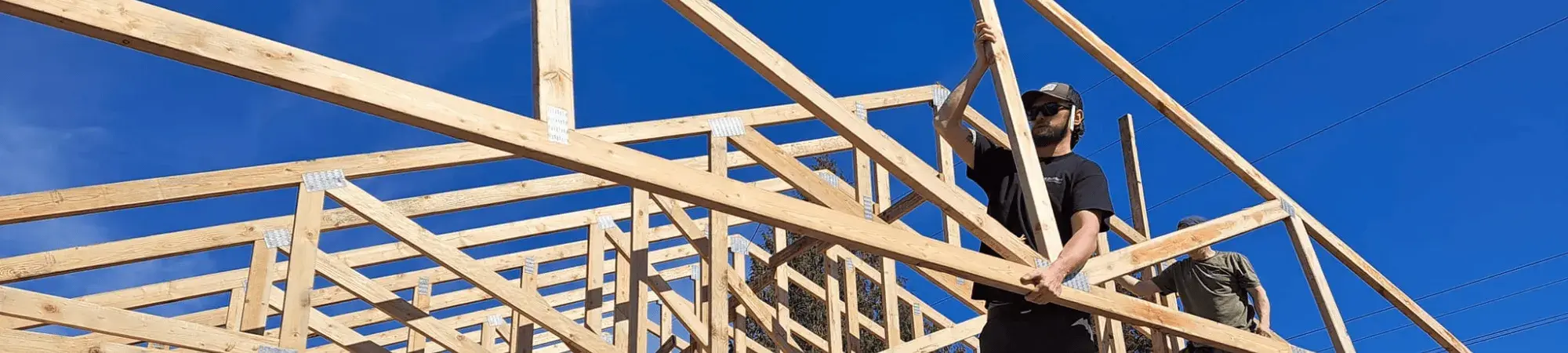 volunteer assisting with the construction of the framing of a roof.