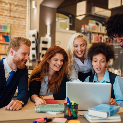 Group of young people gathered around a laptop