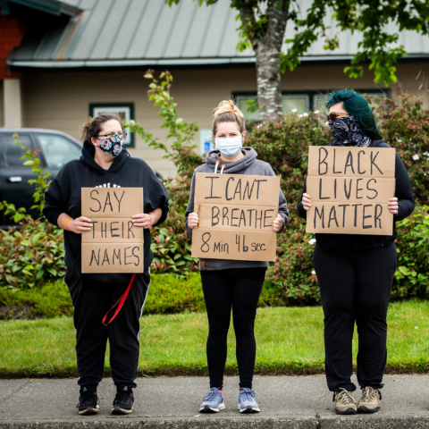 Three people standing on a sidewalk holding BLM signs