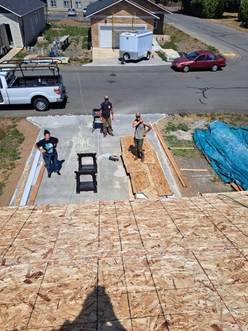 view from the roof of a house under construction of three people standing in the driveway