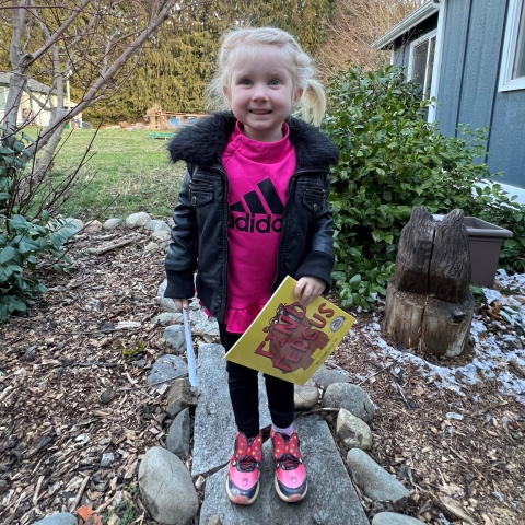 3-year old girl smiling and holding a book