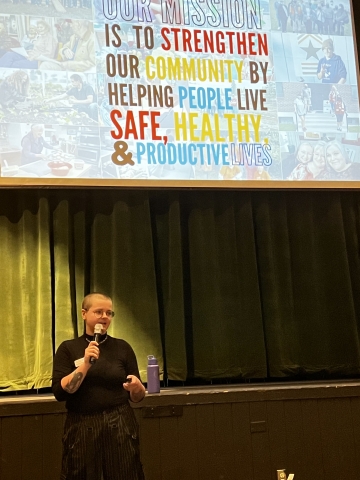 Person with shaved head standing in front of presentation slide