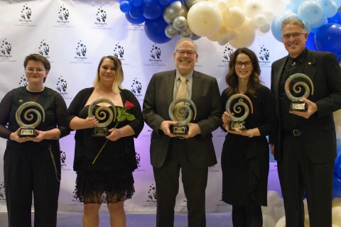 Five people holding awards