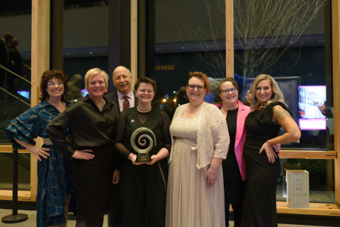 Group of people smiling as one holds an award