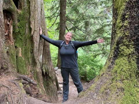 Smiling woman with arms outstretched between trees