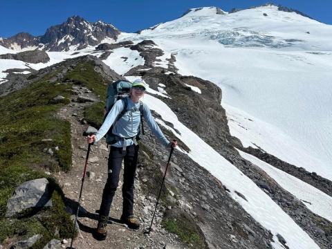 Woman on top of mountain ridge holding walking sticks