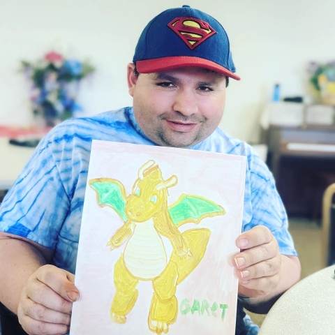 young man holding a drawing of a dragon