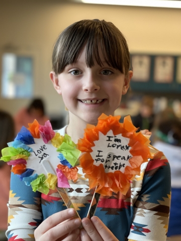 Smiling girl holding two craft flowers