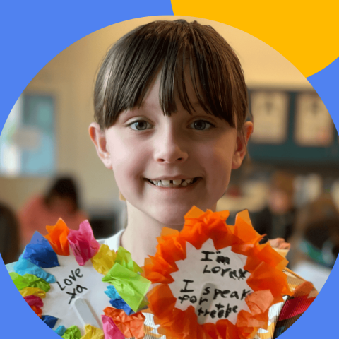 Smiling girl holding two flowers made from tissue and paper