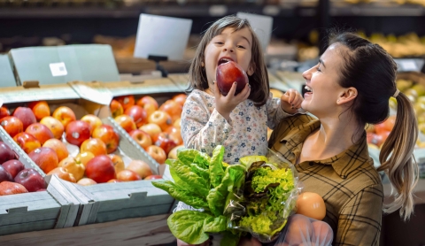 Mom holding little girl holding an apple