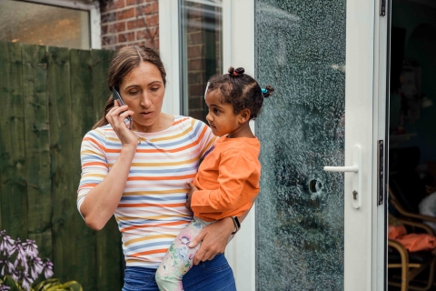 Woman holding baby while talking on phone