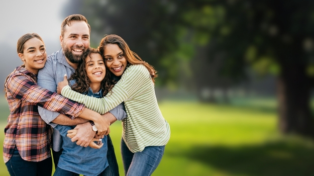 A smiling family hugging in a park