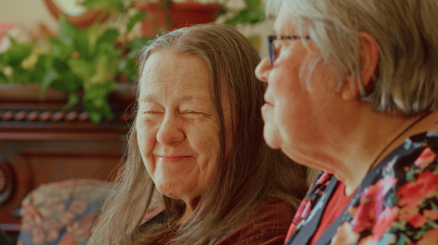 Two elderly women sitting together smiling