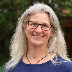 A smiling woman with grey hair and glasses