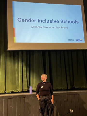 Person with shaved head standing in front of presentation screen