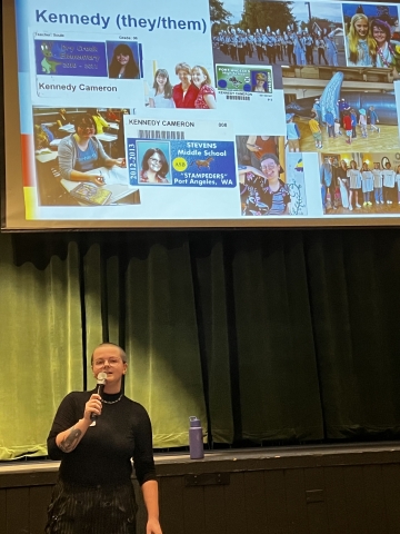 Person with shaved head standing in front of presentation screen