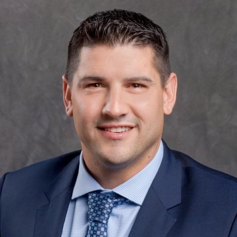 Headshot of a smiling man in suit and tie